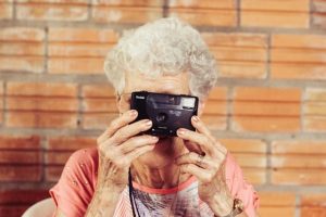 Ældre dame tager billede med et kamera.